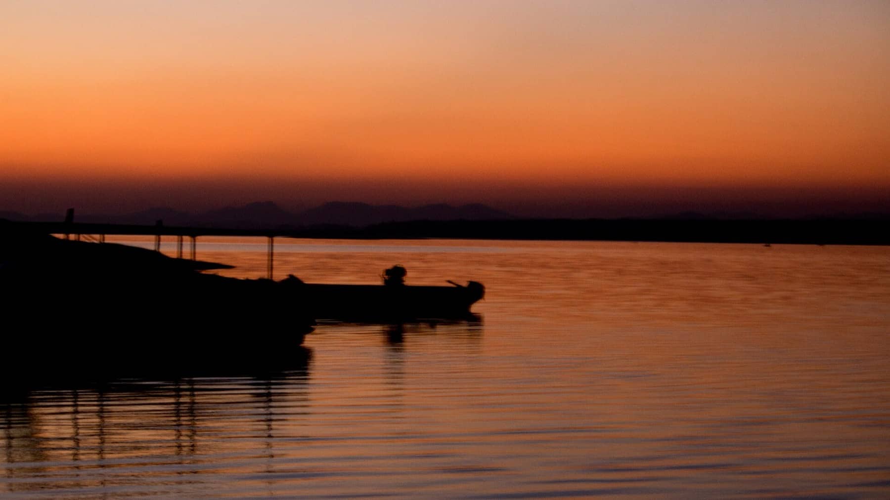 A safari boat comes home across the Denwa at dusk