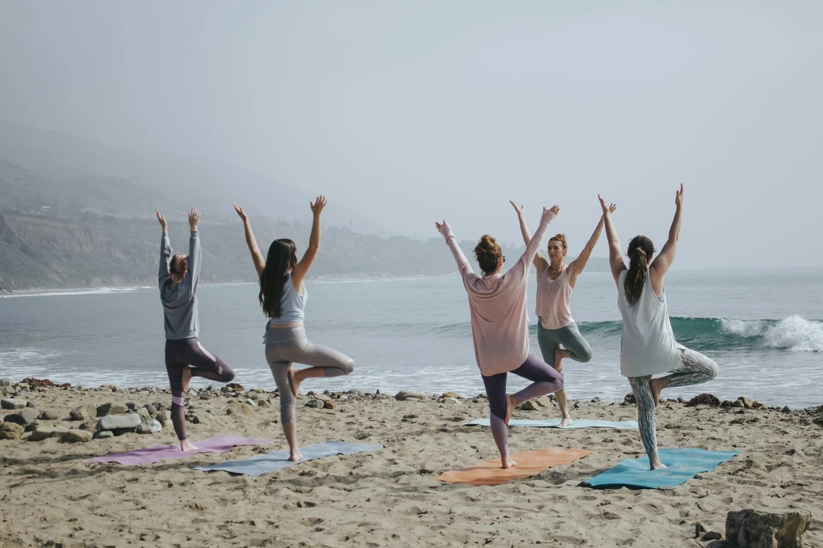 A group practising yoga together on a beach